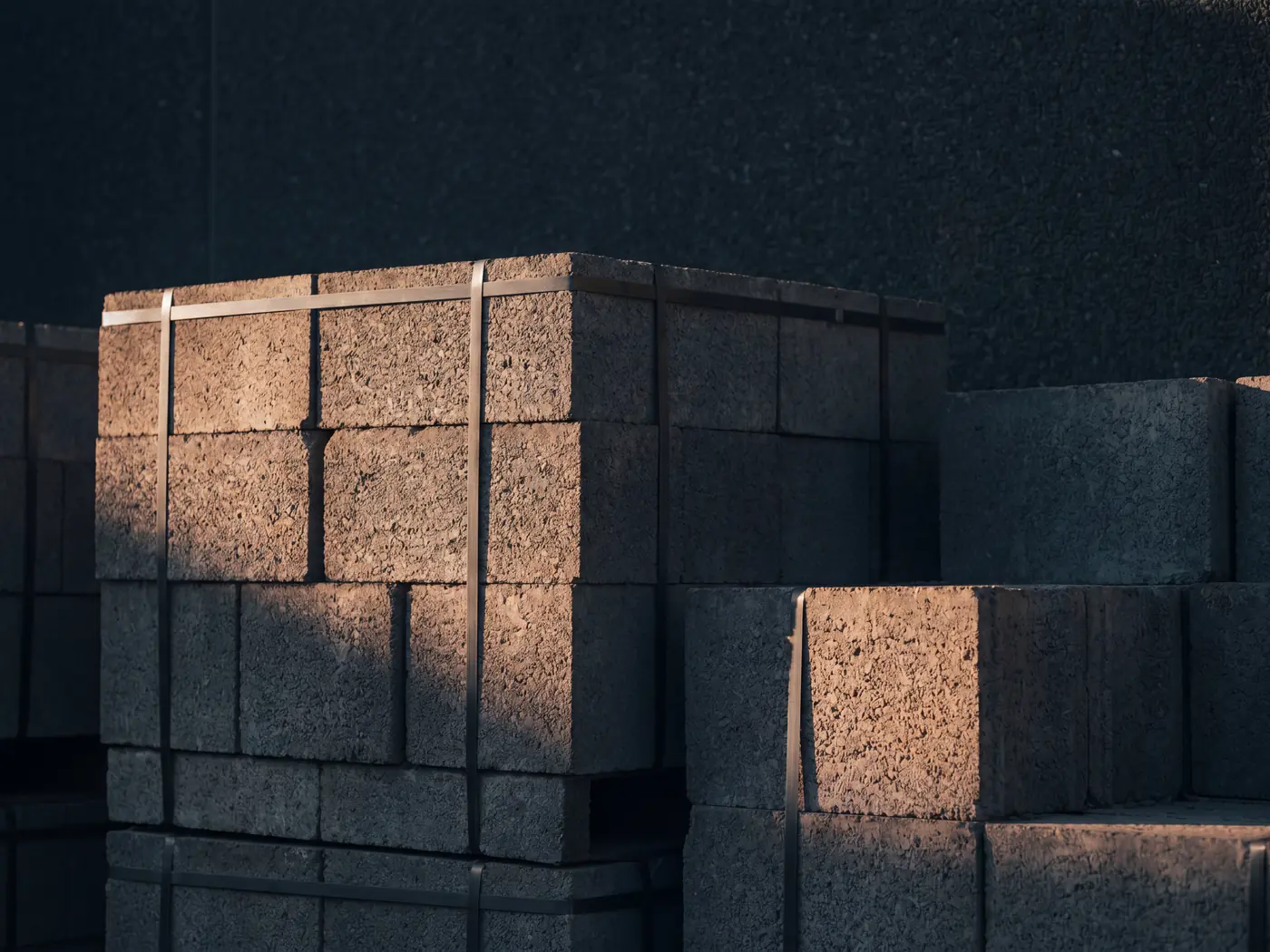 Banded stacks of dense concrete blocks, clean cast edges catching warm side light